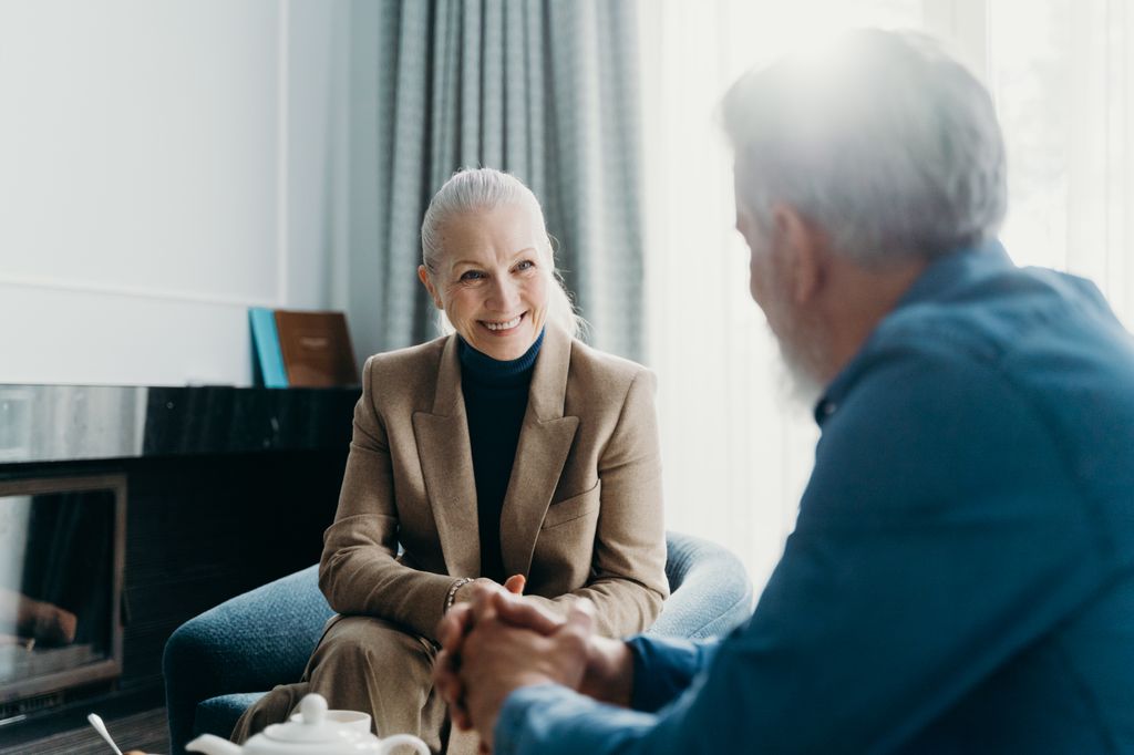 A senior couple enjoying a cheerful conversation in a cozy living room setting.